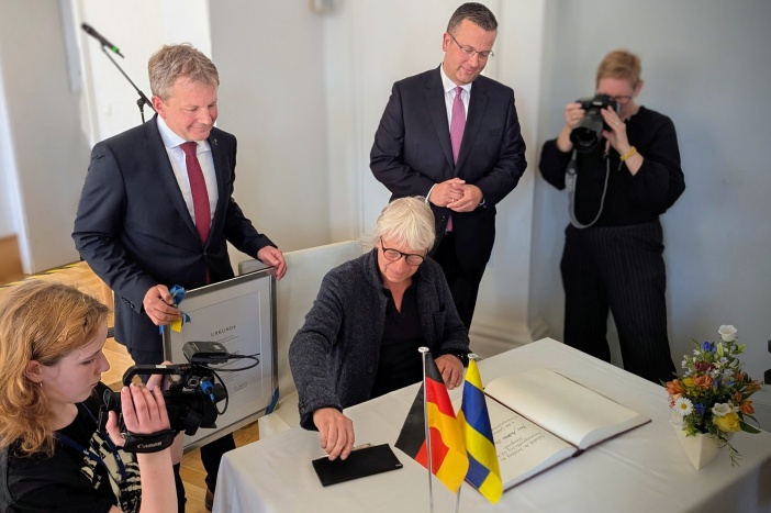 Andreas Dresen trägt sich im Beisein von Oberbürgermeister Rico Badenschier (links) und Stadtpräsident Sebastian Ehlers in das Goldene Buch der Stadt ein. © Landeshauptstadt Schwerin/Ulrike Auge