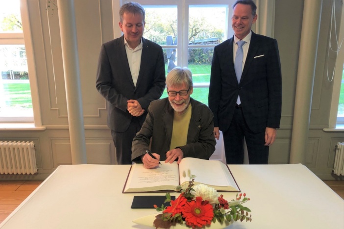 Landeskulturpreisträger Dr. Wolf Karge trägt sich im Beisein von Oberbürgermeister Dr. Rico Badenschier (links) und Kulturdezernent Silvio Horn (rechts) in das Goldene Buch der Stadt ein. © Landeshauptstadt Schwerin